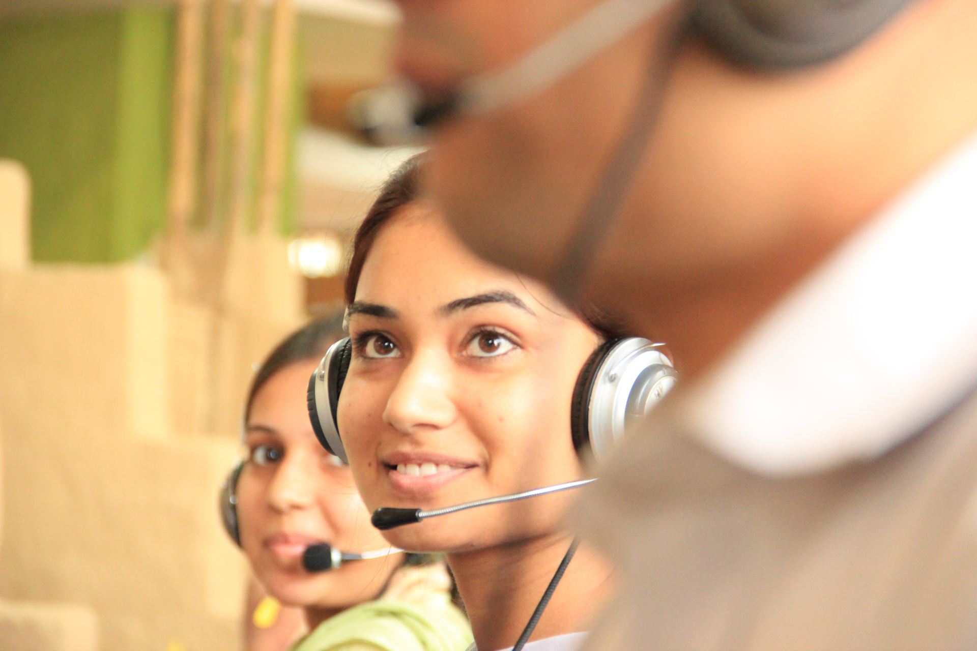 A smiling lady with a headset on working in a call centre