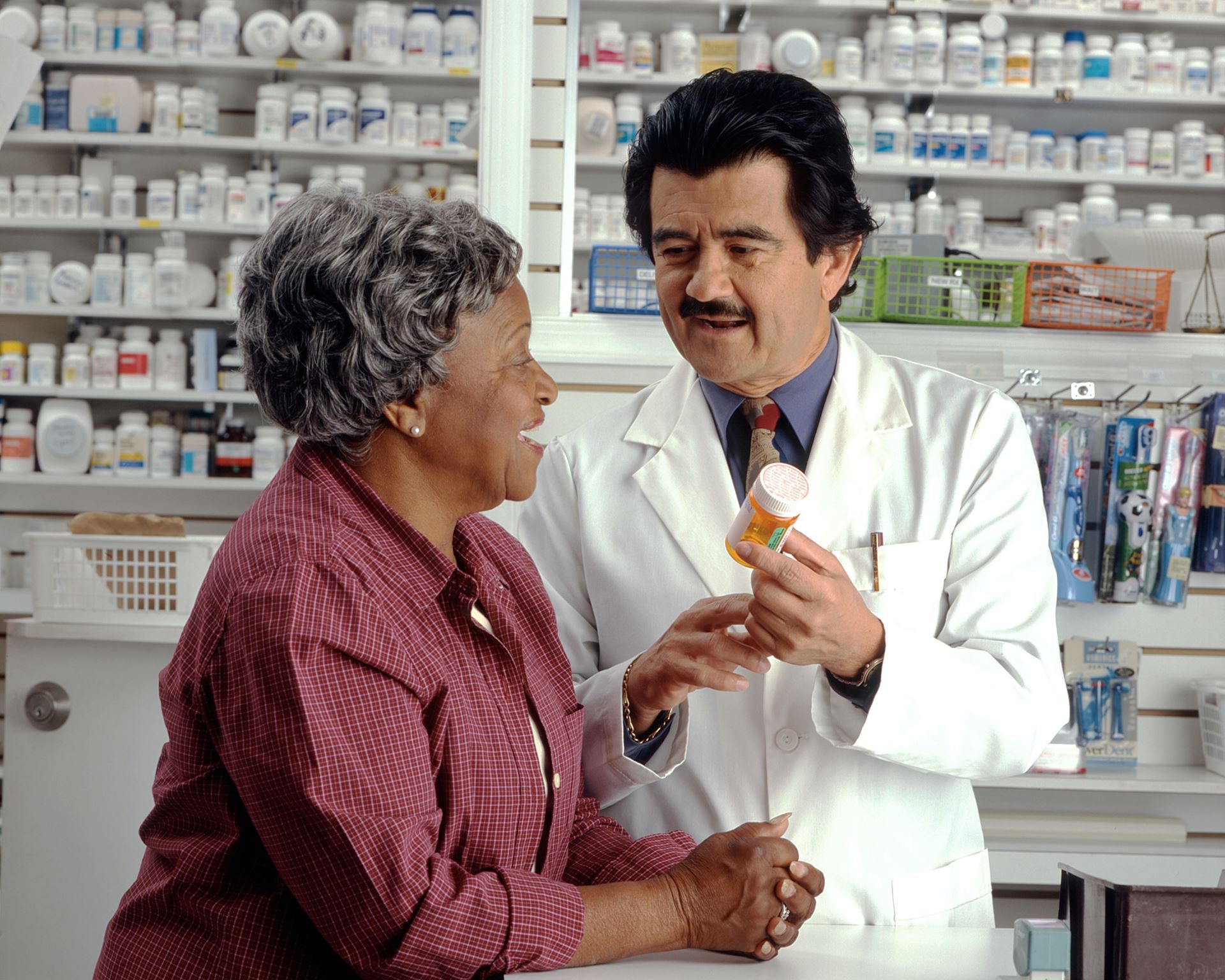 A pharmacist showing a lady a bottle of pills