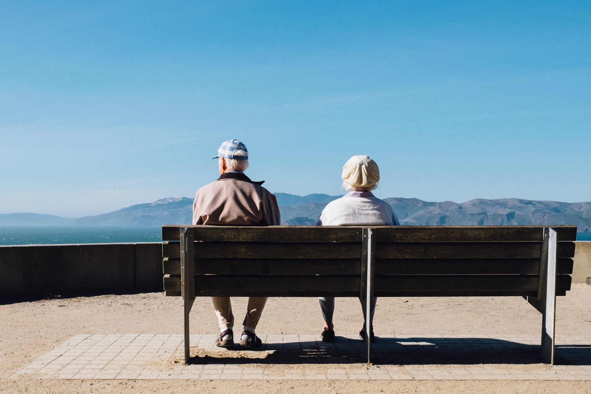 Two older people sitting on a bench looking out at the view
